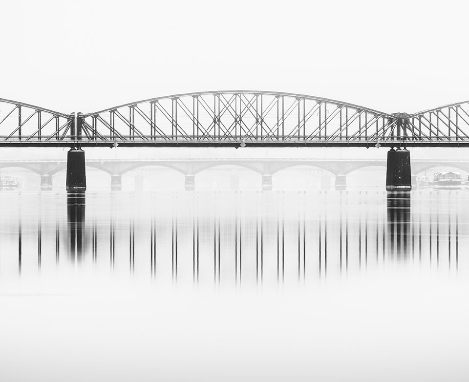 Foggy winter mood at Vltava river. Reflection of bridges in water. Black and white atmosphere, Prague, Czech republic