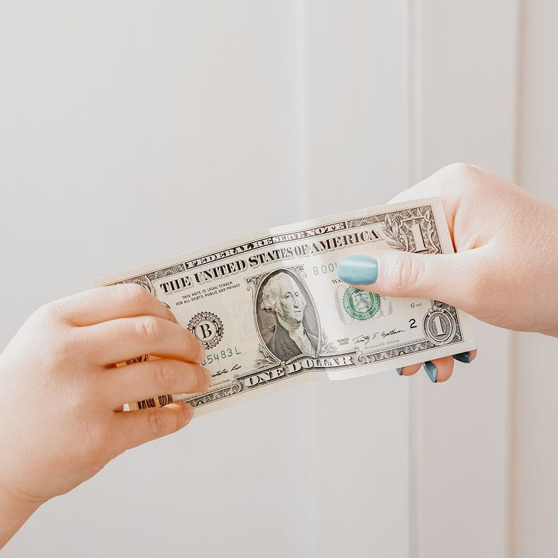 pocket money concept. woman’s hand giving dollar note to a child.